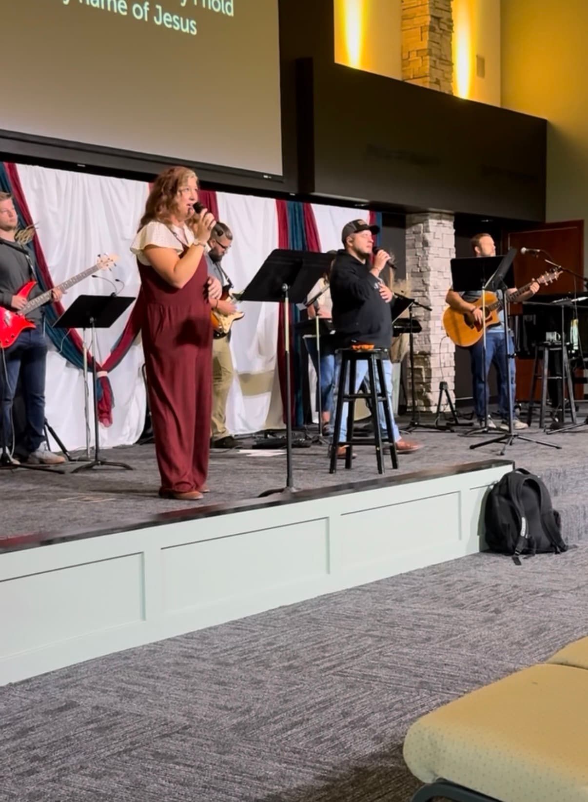 A woman singing in worship beside a band at a Church For Pastors service.